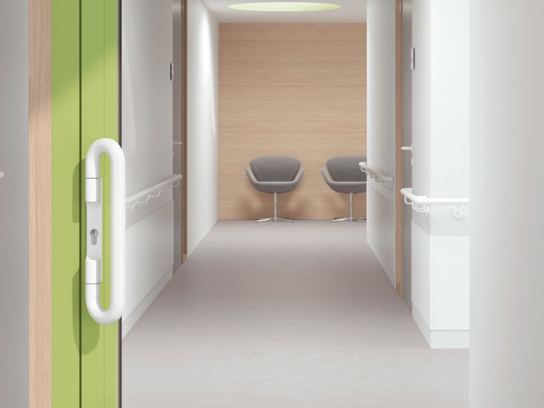 Glazed hospital door with green frame equipped with a lever handle in the colour signal white made of polyamide