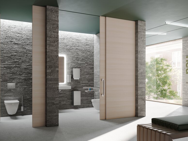 Öffentliche, barrierefreie WC-Kabine mit Stützklappgriffen,  Seifen- und Papierspender in Edelstahl matt